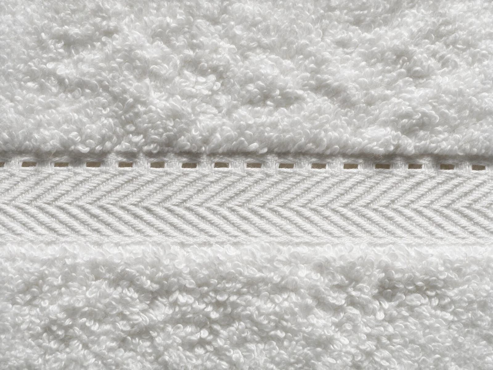 Macro photograph of a white towel’s woven dobby border next to its terry pile