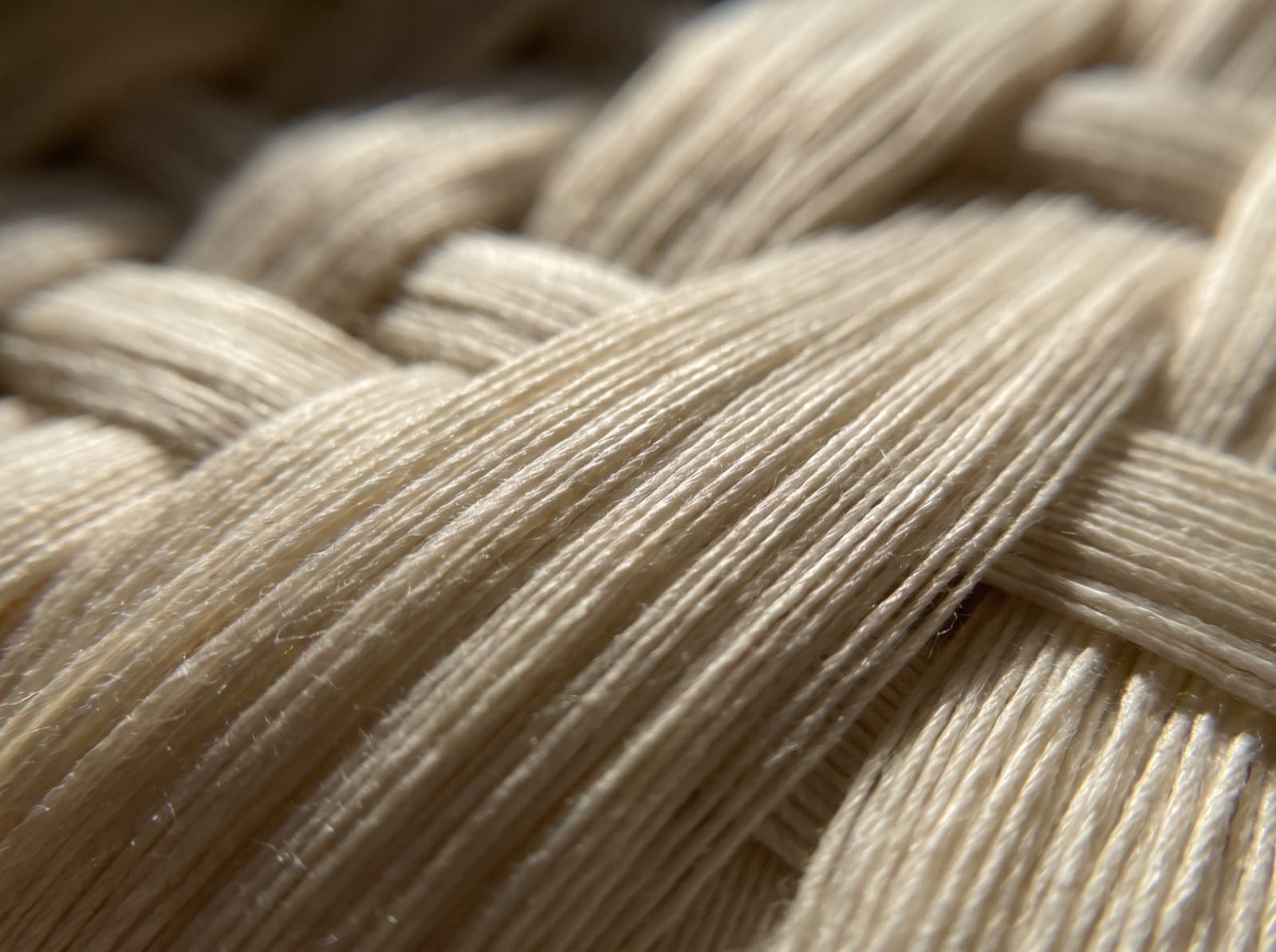 Extreme macro of woven long-staple Egyptian cotton yarns showing the dense over-one under-three sateen weave structure and smooth fibers